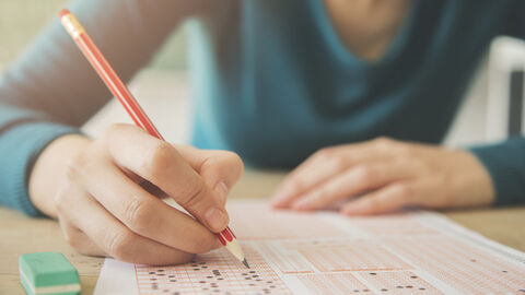 Hand mit Bleistift schreibt auf Bogen