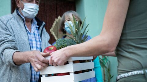 Eine Kiste mit Obst und Gemüse wird übergeben