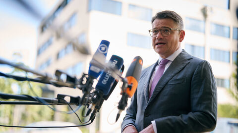 Hessischer Ministerpräsident Boris Rhein steht vor Mikrofonen und spricht