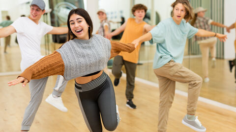 Gruppe Jugendlicher lacht und tanzt  in einer Tanzschule