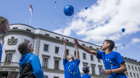 Kinder lassen vor dem Landtag Luftballons mit einer Friedsbotschaft steigen