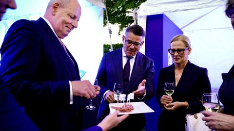 Ministerpräsident Rhein und zwei weitere Personen bekommen einen Teller mit Salami hingehalten.