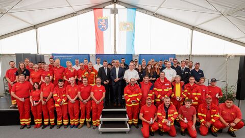 oman Poseck steht gemeinsam mit Vertreterinnen und Vertretern des Brand-und Katastrophenschutzes auf Bühne in Zelt