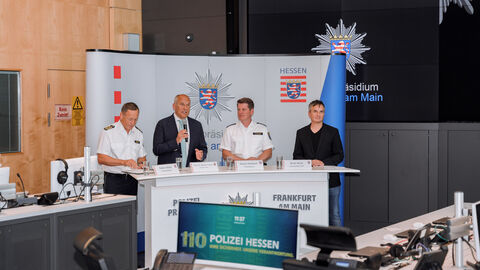 Innenminister Poseck steht gemeinsam mit anderen Beteiligten an einem Stand und stellt die KI-gestützte Videoanalyse vor.